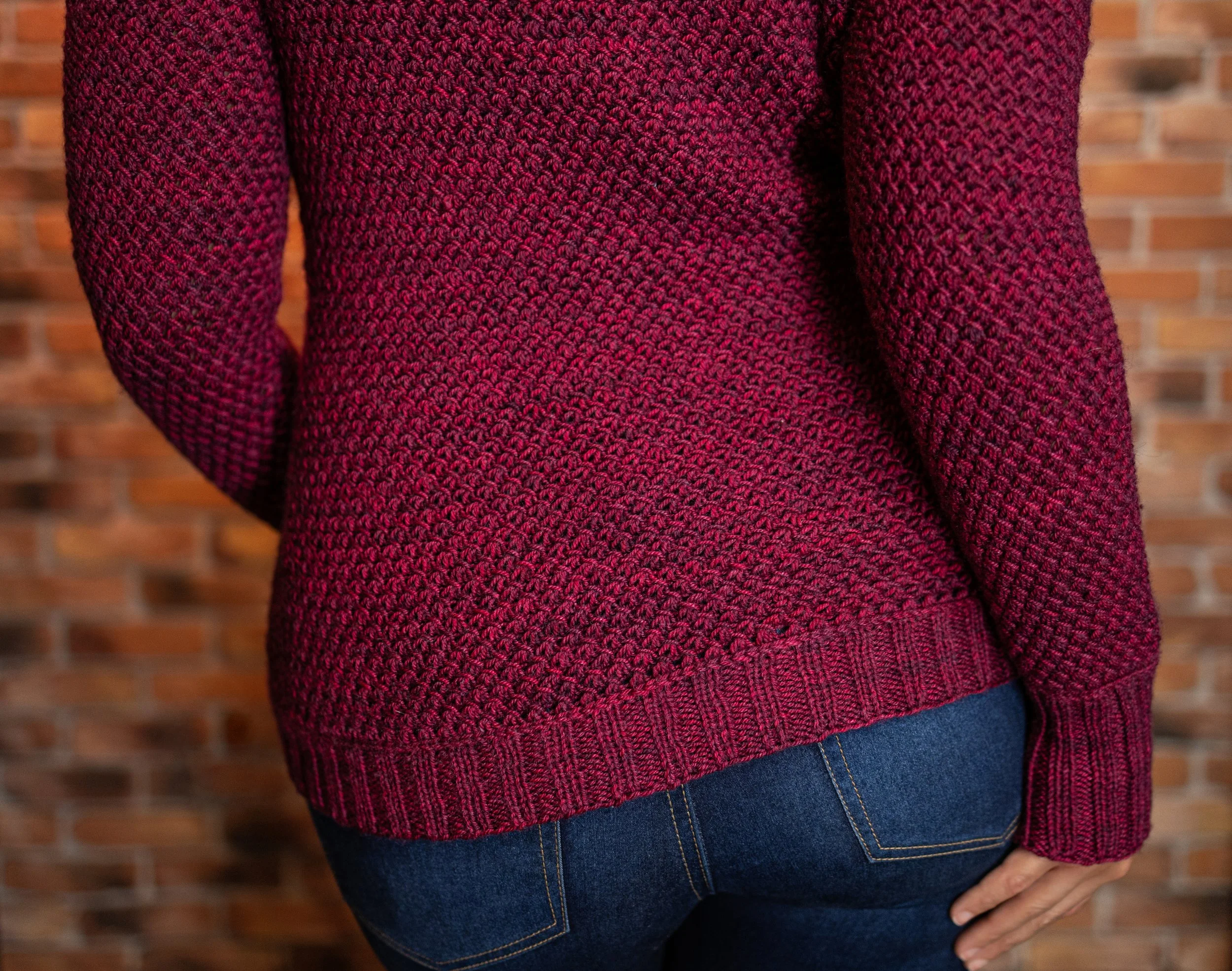 Back view of the handknit fabric in the Nydia Cardigan, combining slipped stitches and yarn overs for a squishy, beautiful fabric that looks like tunisian crochet framed by lateral braids and 2x2 rib.
