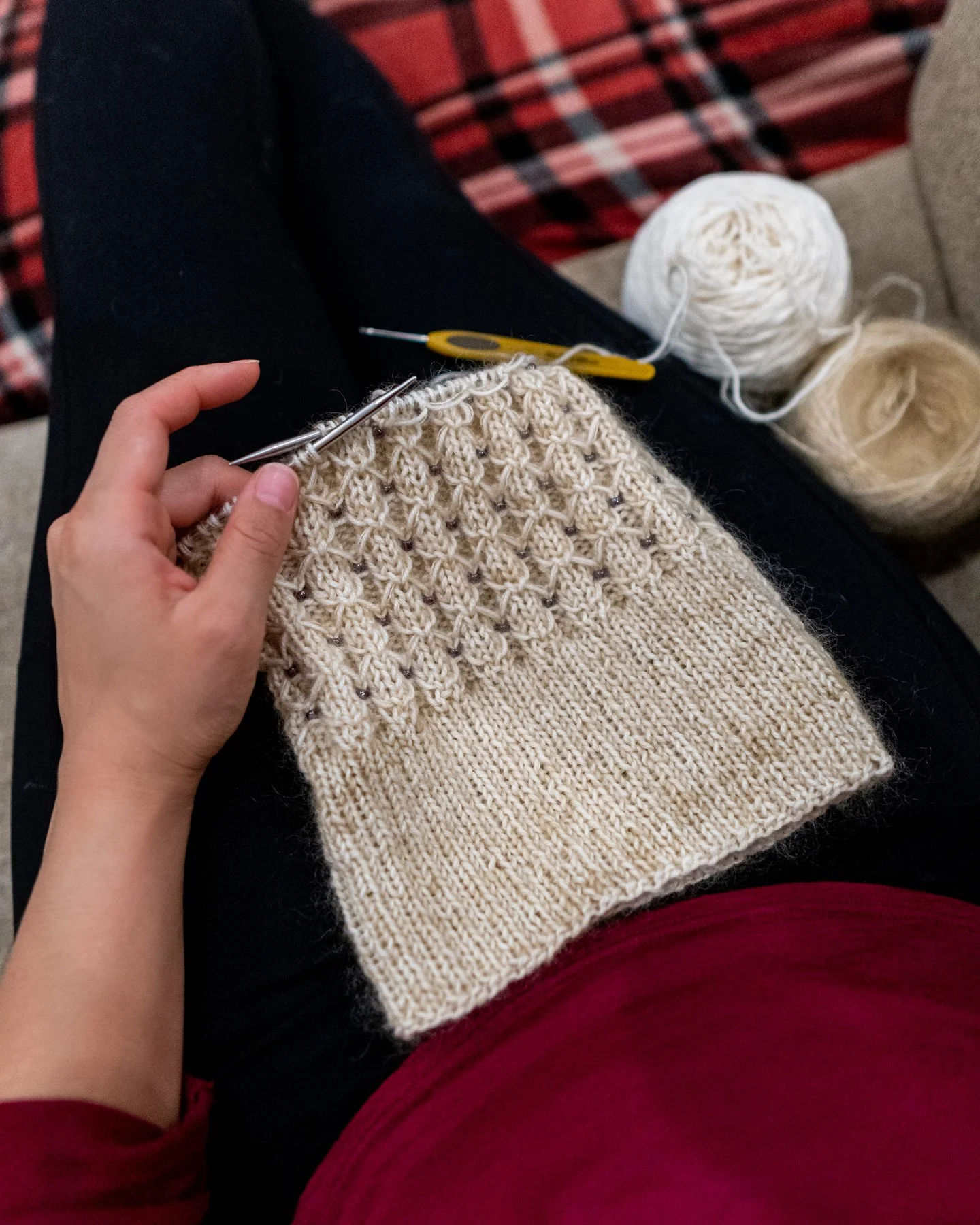 Knitwear designer Vanessa Smith spends a cozy evening working on a cream-colored Stars Hollow hat, a knitting pattern inspired by the TV show Gilmore Girls with easy ribbing, beads, and a folded brim.