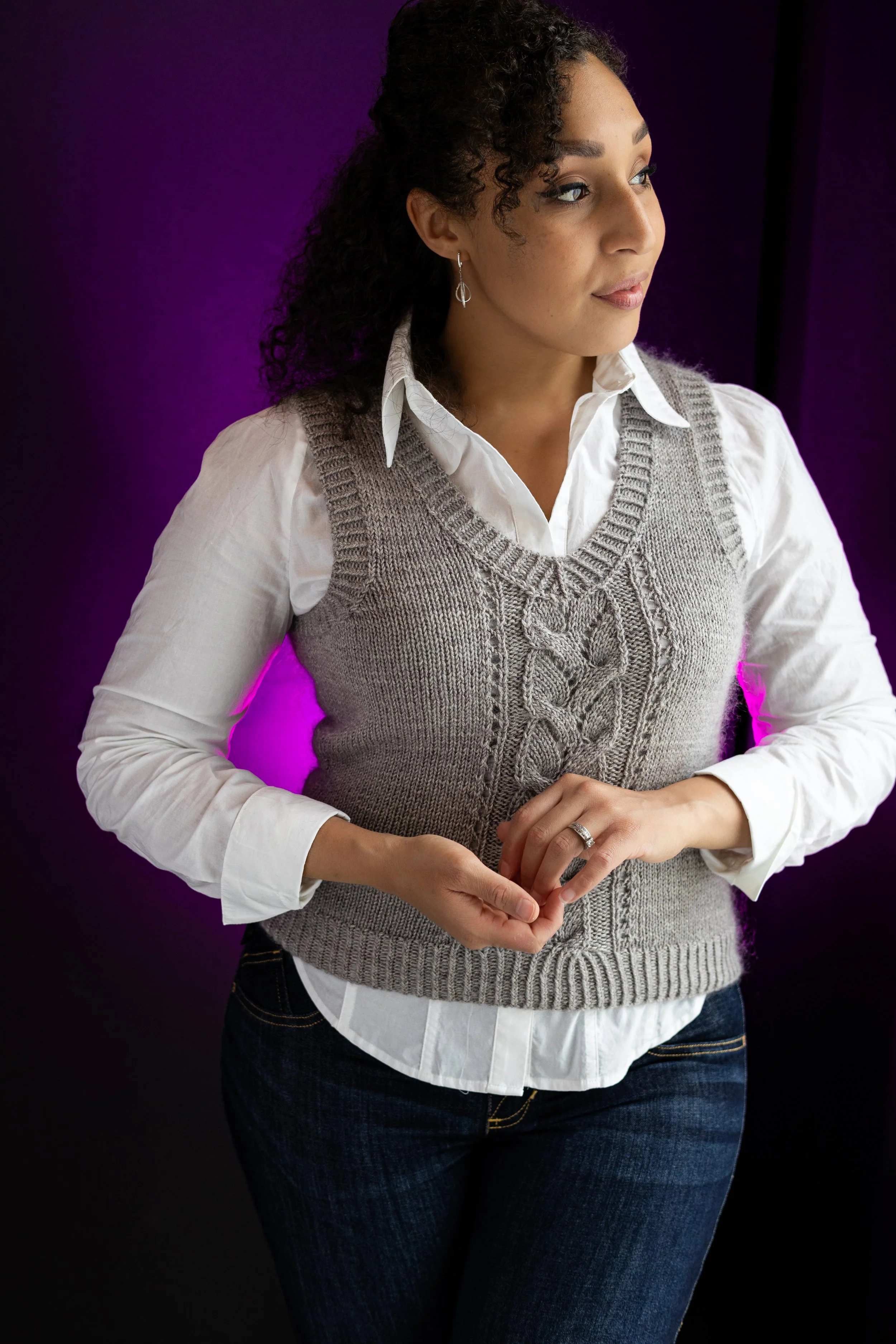 Woman looking chic & comfortable in a mid-length, gray Bestie Vestie, layered over a collared shirt and perfect for a smart casual look. PDF, size-inclusive knitting pattern by Vanessa Smith Designs.