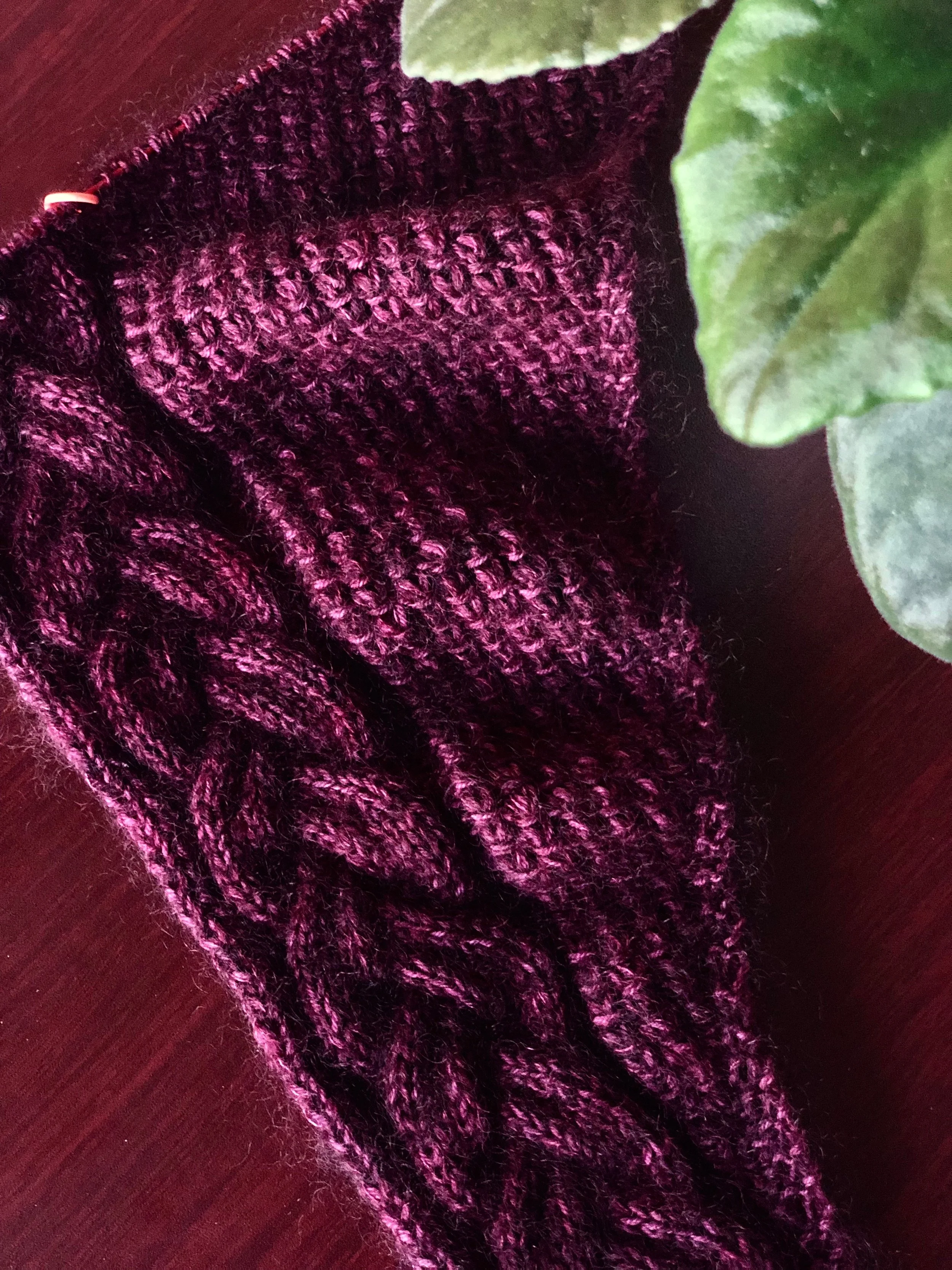 In-progress photo of Indira, a triangular knit shawl that begins with just a few stitches and grows gradually to its full size. A double-braided cable travels alongside a textured lace stitch pattern.