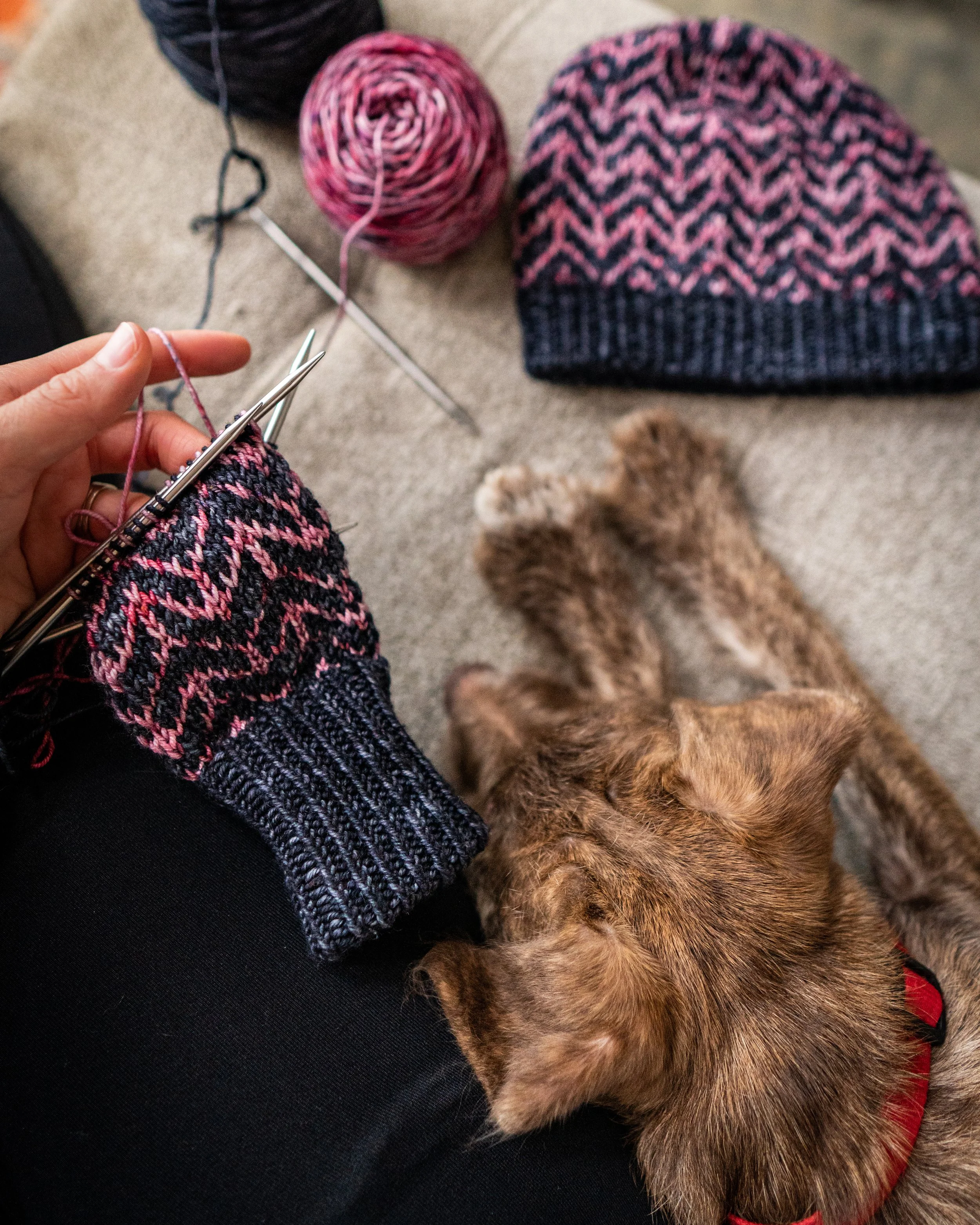 Two-color fingerless glove being handknit on double-pointed knitting needles & using the stranded colorwork technique to create a bold geometric chevron motif following a double, 1x1 twisted rib cuff.