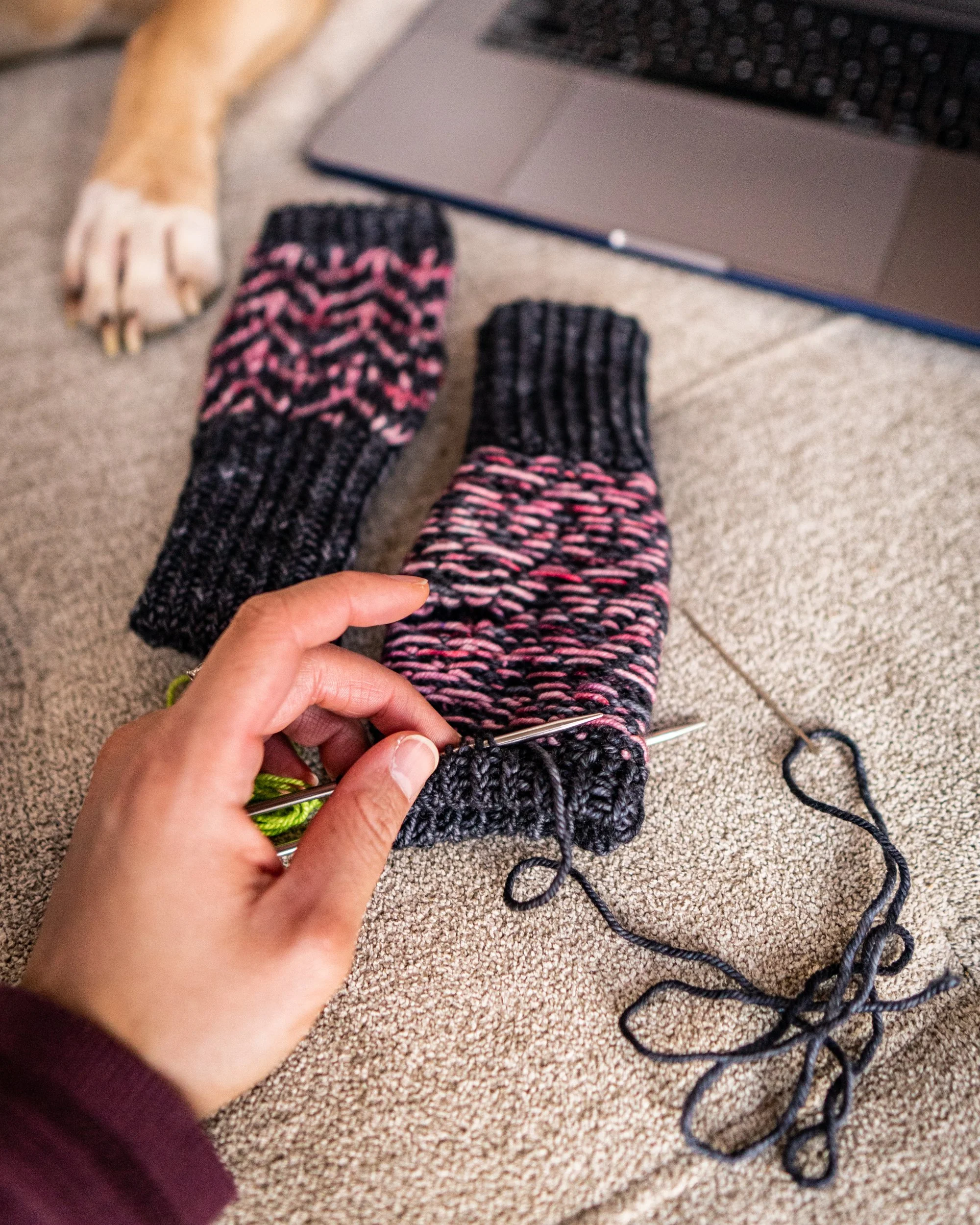 Detail shot of a stranded colorwork work knitting project in progress, showing both the right side chevron stitch pattern and the wrong side floats as well as the process to tack down the folded hem.