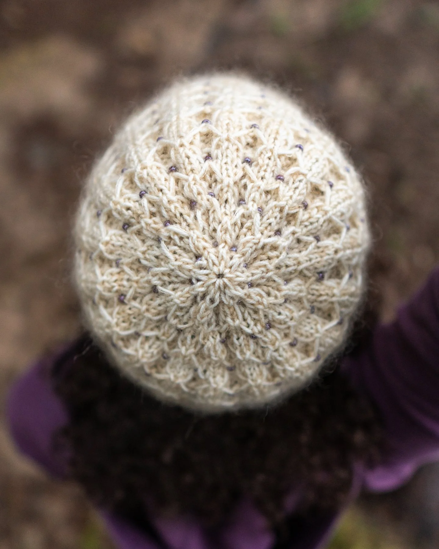 Top-down view of the elegantly detailed, beaded crown of the Stars Hollow hat handmade in a cream sport weight wool held together with mohair/silk lace. Cozy rib knit beanie inspired by Gilmore Girls.