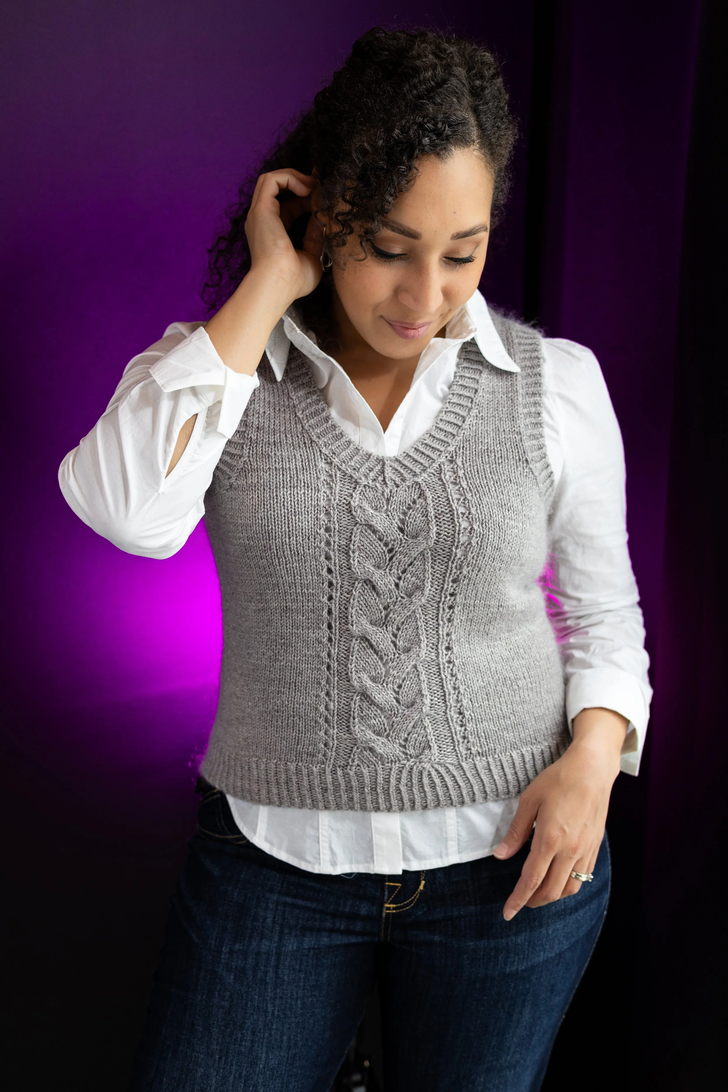 An alternative styled view of the versatile Bestie Vestie knit slipover, an essential knitted layer with a striking cable and lace panel and V neckline. PDF knitting pattern by Vanessa Smith Designs.