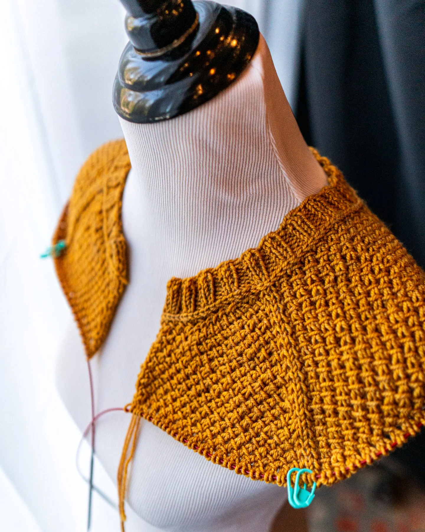 Detail shot of a warm yellow Nydia Cardigan in progress, showing the classic, round neckline; horizontal braid; and compound raglan shaping in this custom-fit women's knitting pattern by Vanessa Smith