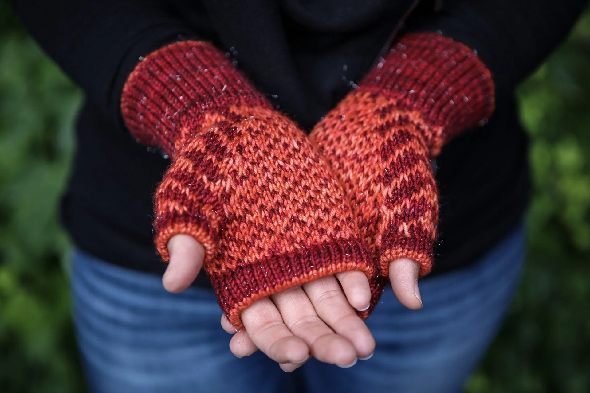 Detailed palm view of a gifted pair of Novemberist mitts in red and orange. A pop of color peeks out from all the double-layer edgings in this thoughtfully designed glove knit pattern by Vanessa Smith