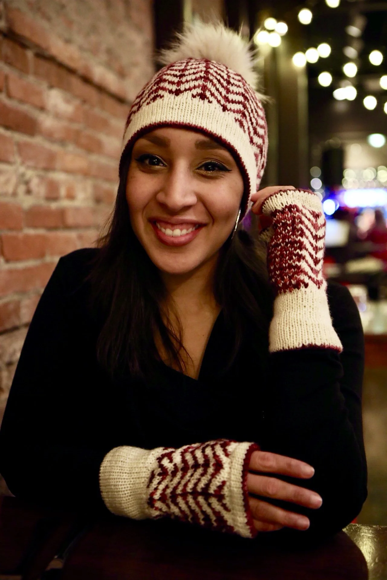 BIPOC knit designer Vanessa Smith proudly wears her first stranded colorwork knitting patterns, the Novemberist hat and mitts featuring easy chevron and speckled motifs in deep red and cream DK yarns.