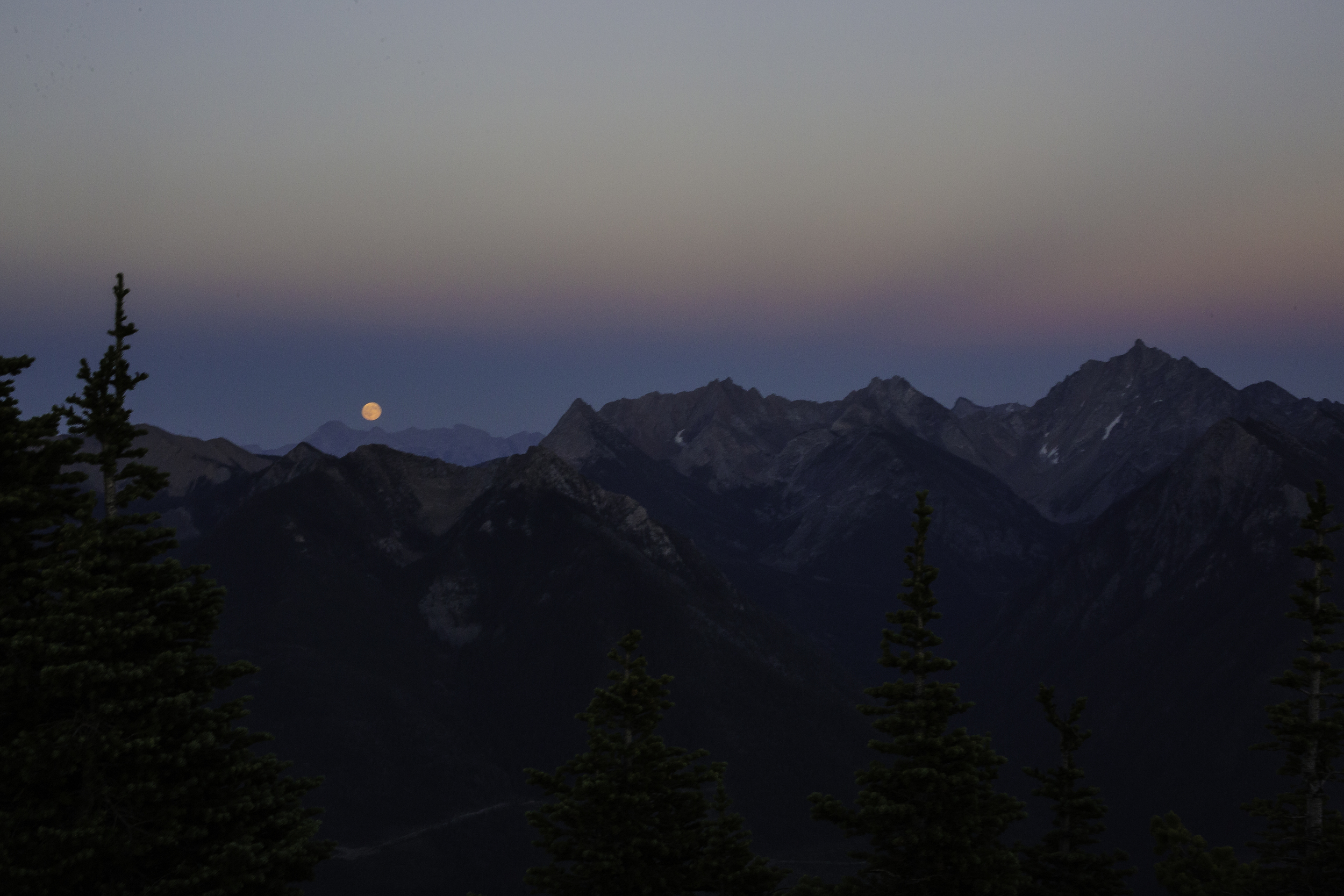 The blue moon rises over the rockies as Fischer Mountain thrusts skywards.