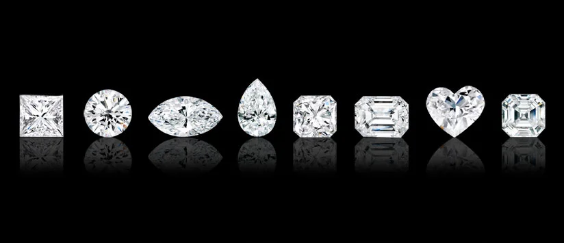 White diamonds in various cuts and shapes. From the left to right, princess square, round brilliant, marquise, pear, radiant, emerald, heart and asscher.