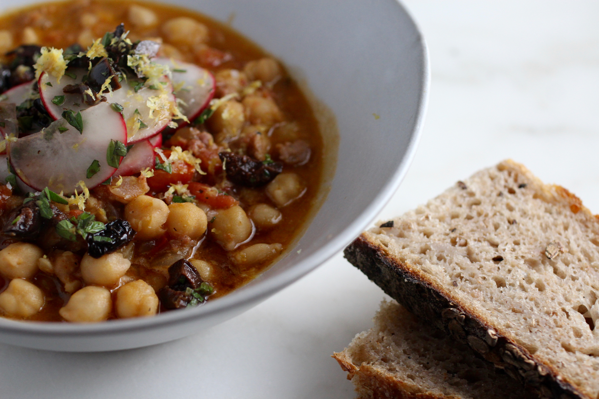 Chickpea soup with preserved lemon juice, tomato, olives, and lemon zest.