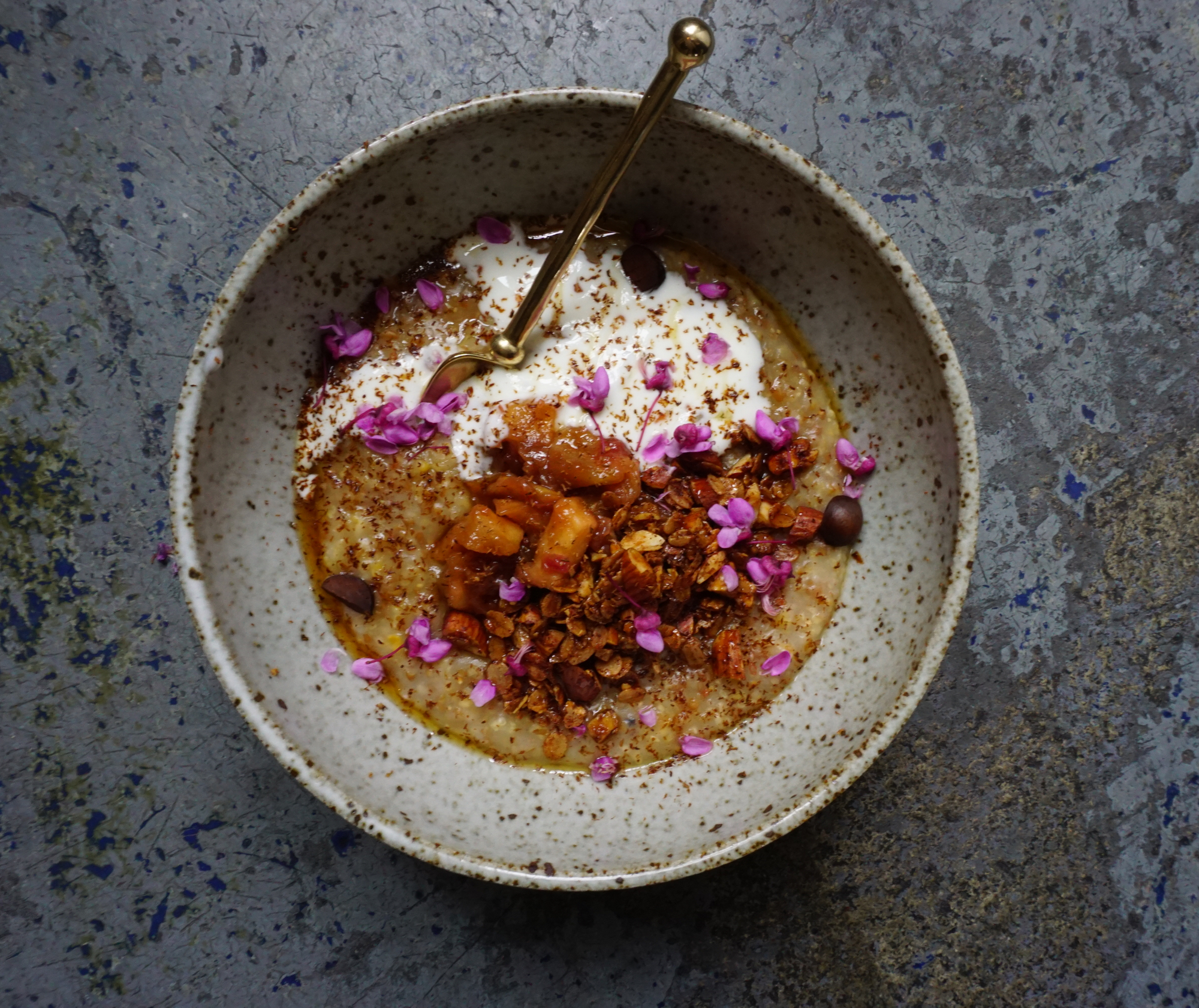 Heirloom grain porridge with feral rhubarb(!) crisp, cardamom, yogurt, maple syrup, bay nut, and red bud flowers.