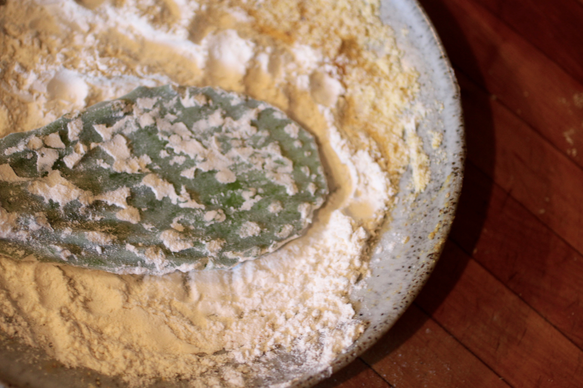 Coating with all-purpose flour before the egg and cornmeal batter.