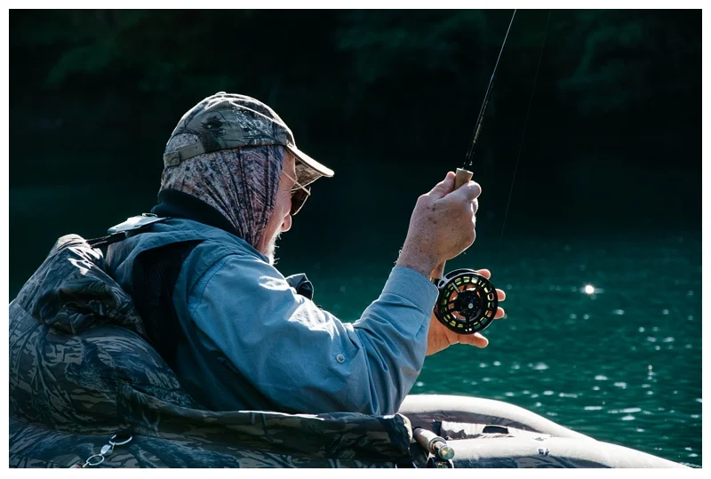 Dick Brashears palms a reel to slow down a fish at Henderson Springs near Big Bend and Redding California. Travel and fishing photography by Max Salzburg of Sonja K Photography.&nbsp;