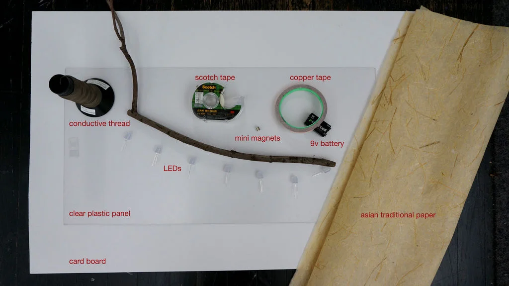 Step 3: Ready to set up on a card board. Materials Necessary: A card board, A clear plastic panel, Asian traditional paper, A branch, 6LEDs, Copper tape, 9v battery, Magnets, Scotch tape, Conductive thread.