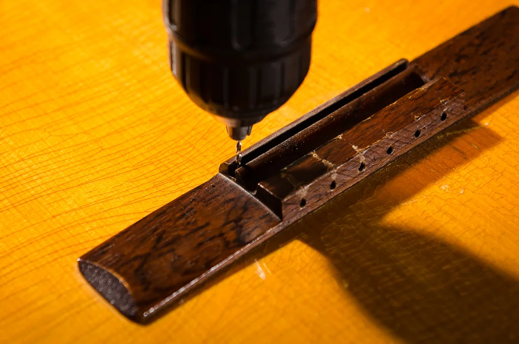 Locating holes drilled into the saddle slot prior to removing the bridge. This makes sure you reglue it back in the same position