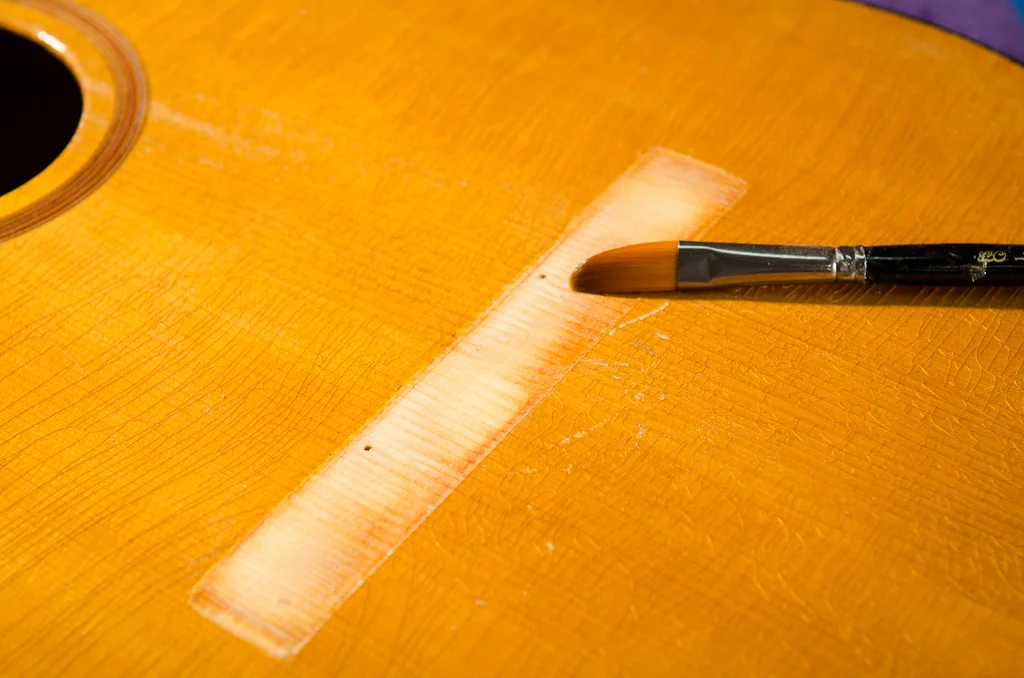 Thinned hot hide glue brushed on bridge footprint to seize the grain. This prevents the top from sucking the joint dry when the bridge is glued