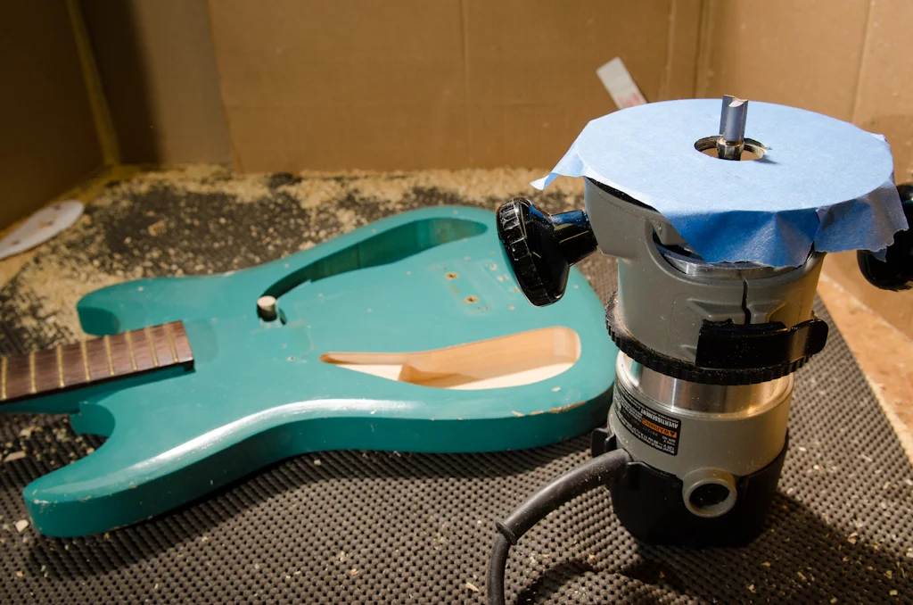 I switch to a bearing router bit to finish off the cavity. The template is removed and the bearing will flush-trim off of the established cavity walls. I tape the base of the router to help protect the guitar’s finish.