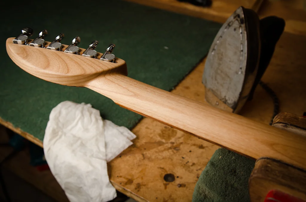 The dampened cloth is placed on the neck over the scratches and the hot iron is pressed onto the cloth, creating steam that expands the damaged wood fibers.