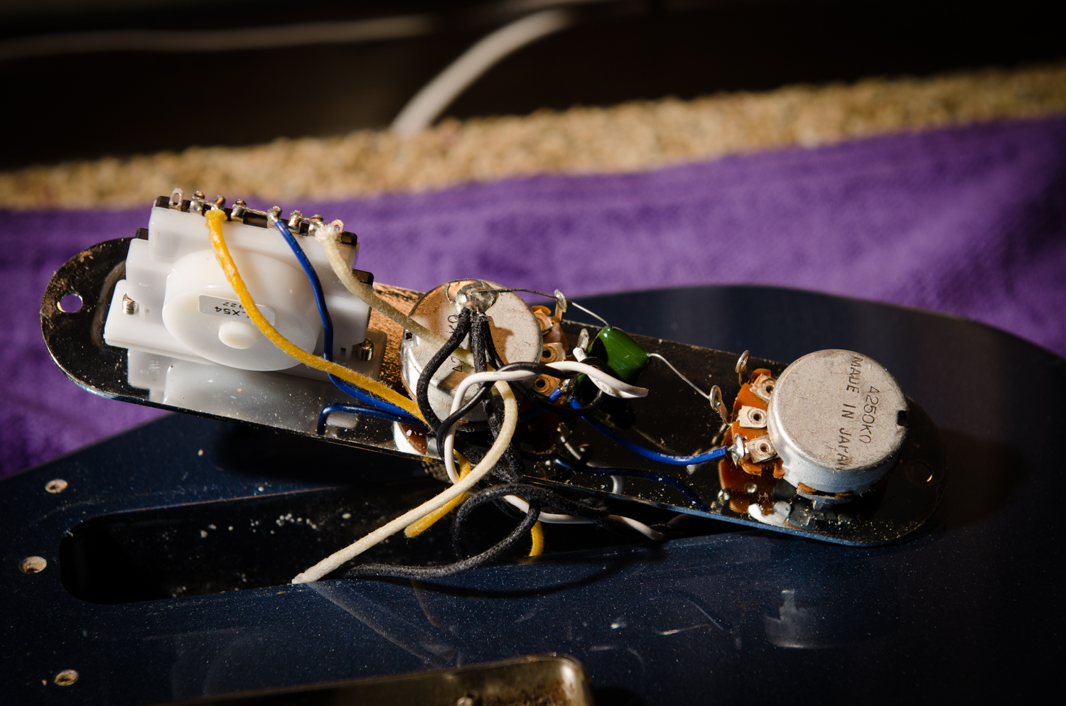 The yellow and white cloth wires are the hot pickup leads on the switch (left) and the black cloth ground wires are soldered to the volume pot case (middle).
