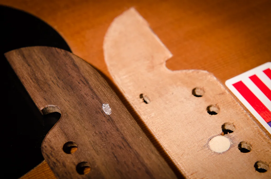 A small piece of aluminum foil is glued into the saddle pickup hole. If this hole is not plugged, glue will end up in the bottom of the saddle slot.