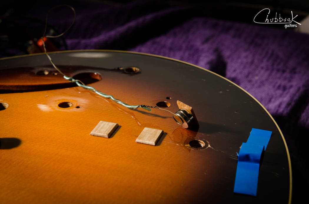 When I find the right position, I tape the exterior magnets down. In order to get the cleats inside the guitar, I use this goofy wire rig to reach in through the f-hole. I’ve used this on a violin before with great results. It is made up of thin military trip wire and a thicker piece of bonsai wire to stiffen a section of it. Double stick tape keeps the cleat on the magnet. Just make sure you get your polarities correct or the magnet will flip over on you inside the guitar when it comes time to install. I work from the farthest edge (right side in this photo) and work back to the f-hole, installing the cleats one by one.