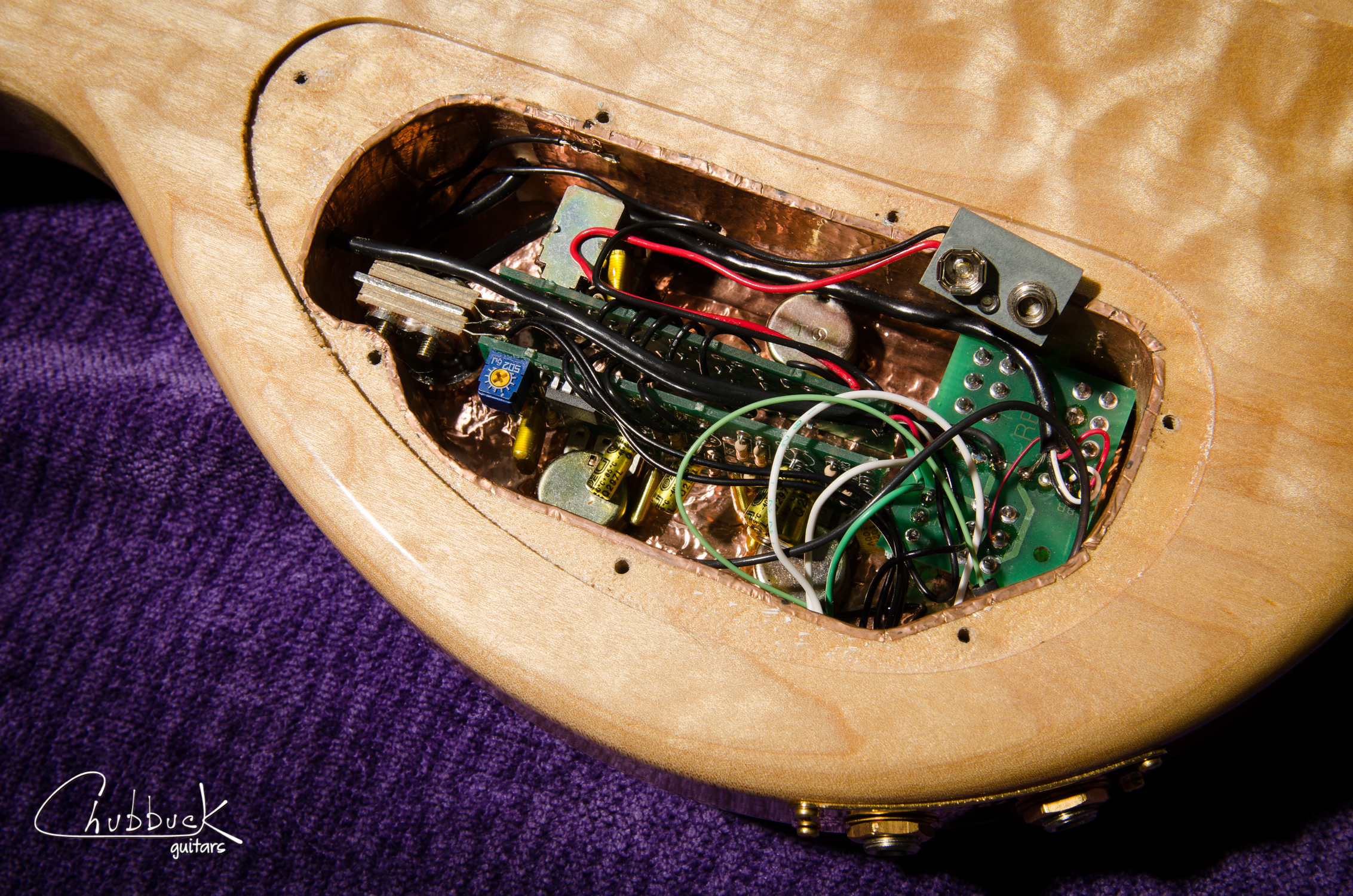 A look inside the control cavity at the active circuit. The controls: neck volume, neck tone, bridge volume, bridge tone, coil taps for each pickup and a phase switch when running both pickups. Note the stereo output jacks to split the signal from each pickup. This will all be removed and converted to passive and mono.