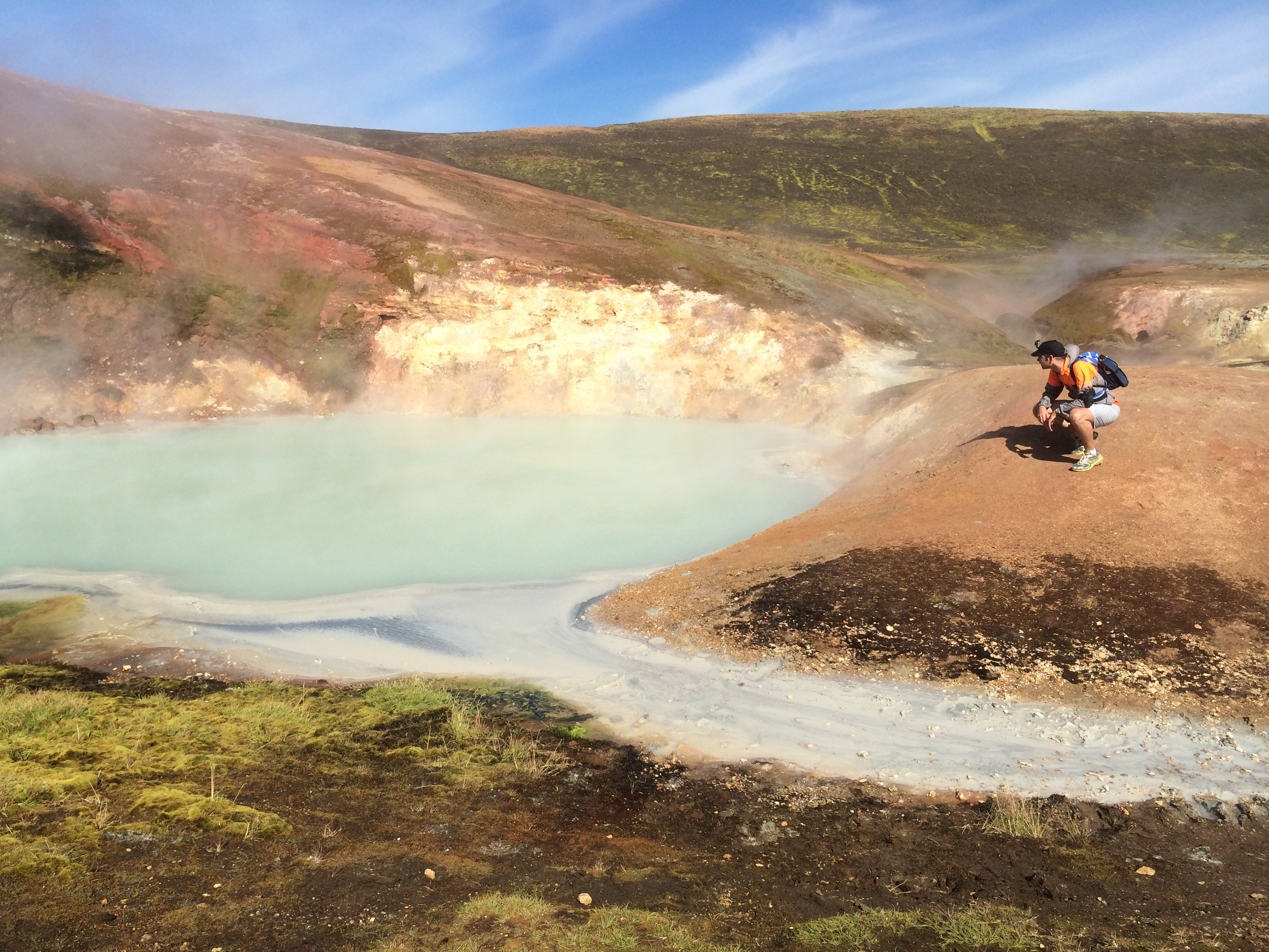A man admire a blue/green-colored hot spring