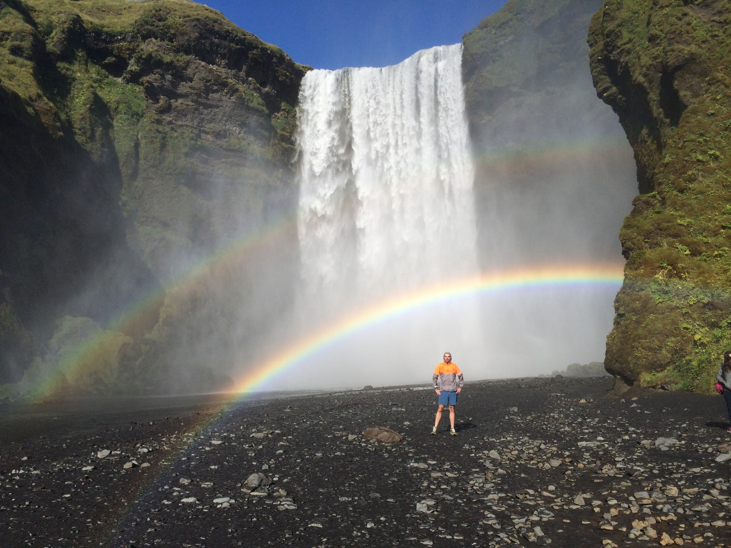 A man, rainbow and Skogafoss