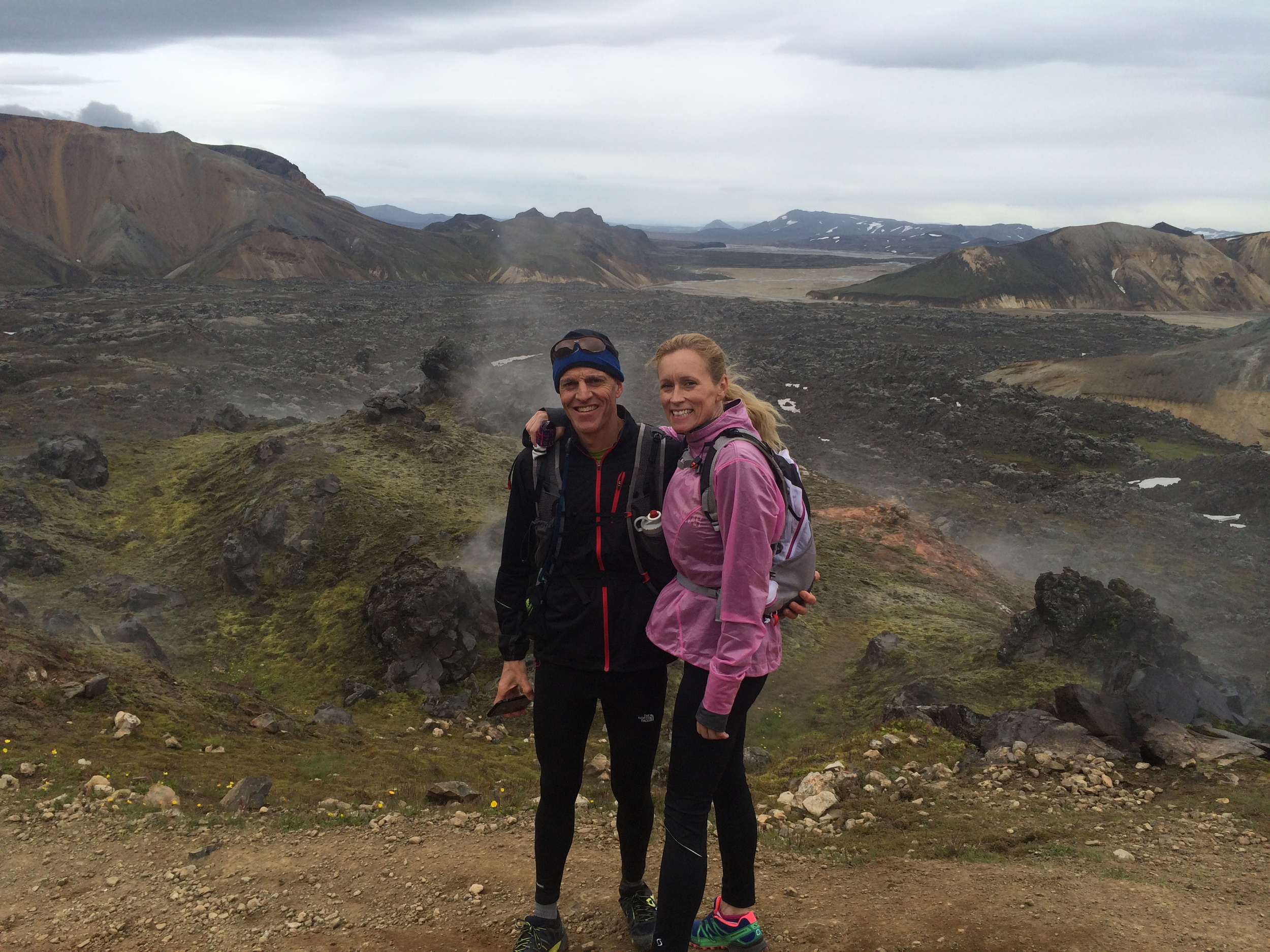 Two lovers getting a rest from running, standing in front of a lava field and a steam.