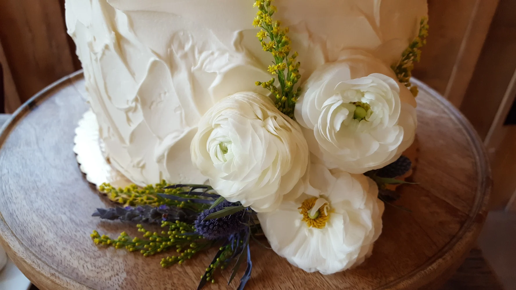 white cake with ranunculus and thistle.jpg
