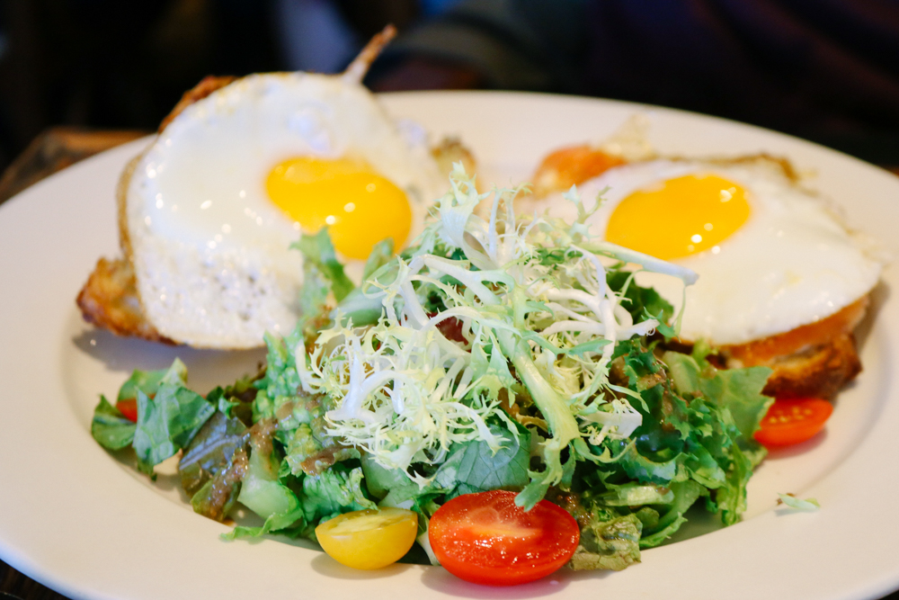 Croissant Oeufs Fromage, 2 Sunny Side eggs, avocado spread, melted mozzarella & gravlax on croissant. Served with mixed greens