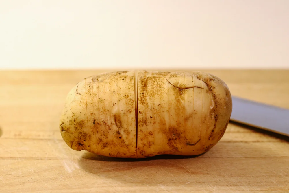Using a sharp knife, make crosswise cuts in each potato, about 1/8 inch apart, stopping about 1/4 inch from the bottom.