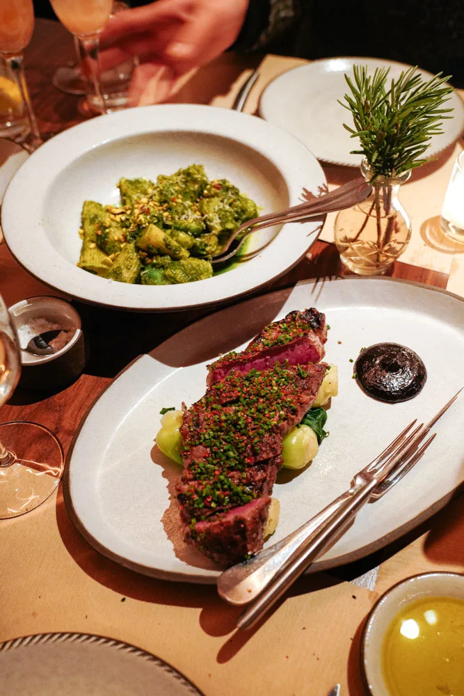 (BACK) RIGATONI, BASIL-PISTACHIO PESTO, CARAMELIZED BRUSSELS SPROUTS (FRONT) SOY-GARLIC MARINATED STEAK, BROCCOLI, FERMENTED BLACK BEAN DRESSING