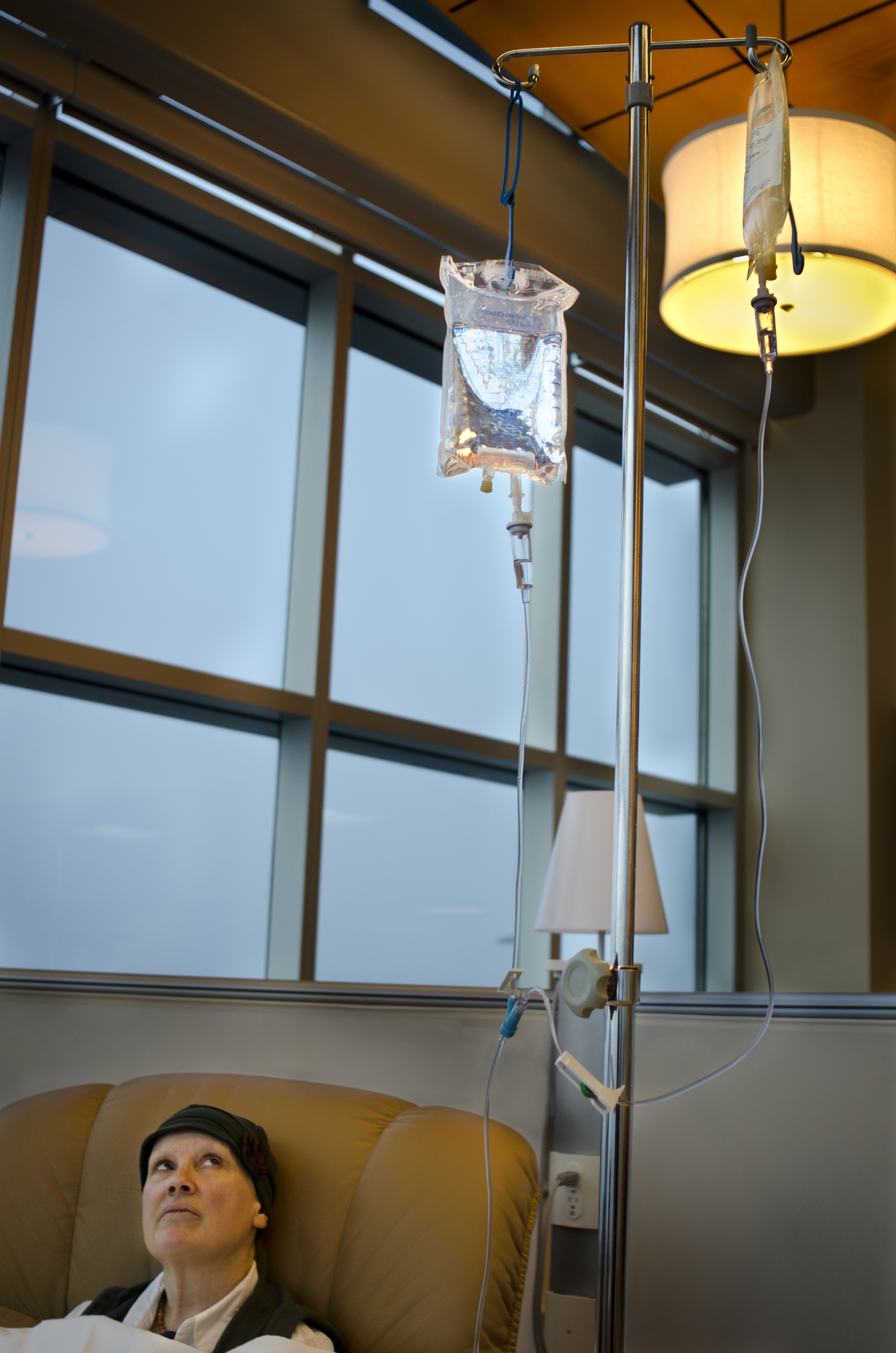 Lois contemplates the chemotherapy bag at her last treatment. She, as do many other cancer patients, has a love/hate relationship with chemotherapy; knowing that it will simultaneously help her but also that she will have to deal with severe side effects.