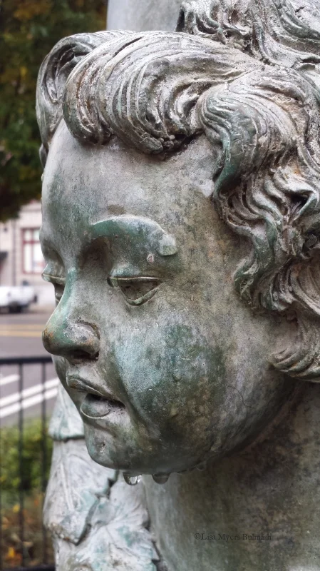 Face of putto on patina'd statue, in Tacoma's antique row district