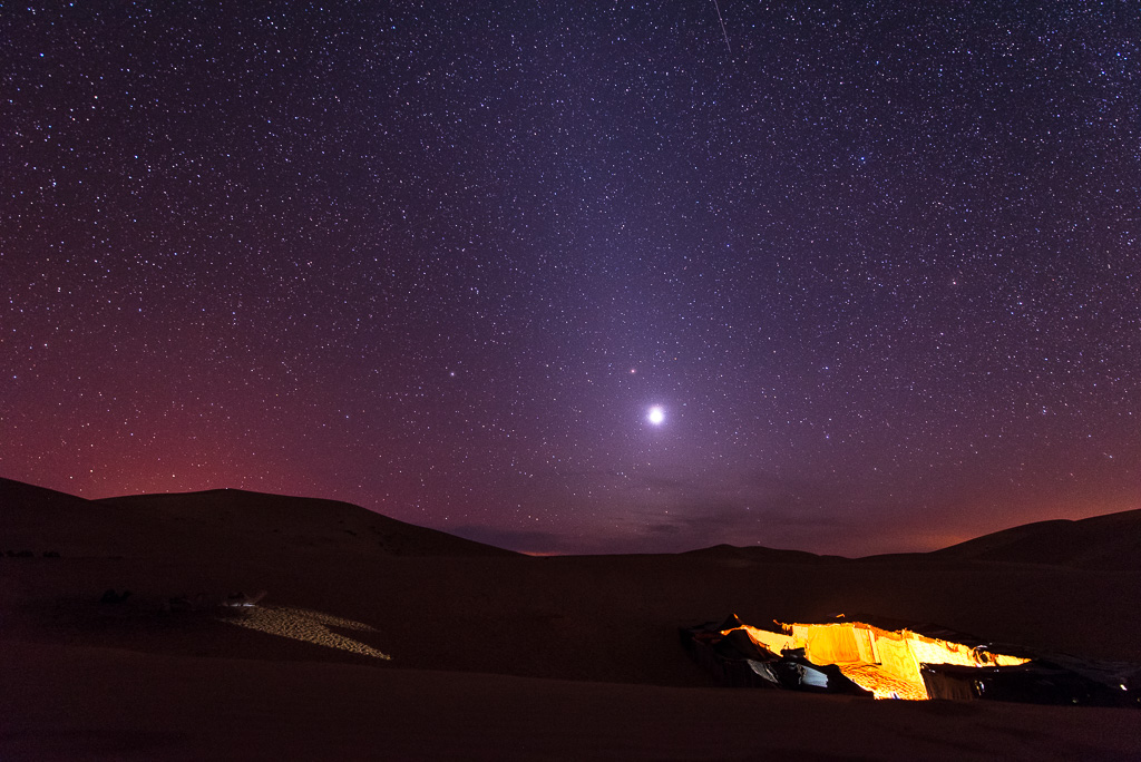 A bright Venus shines amongst the stars over a Berber camp in the Sahara Desert.