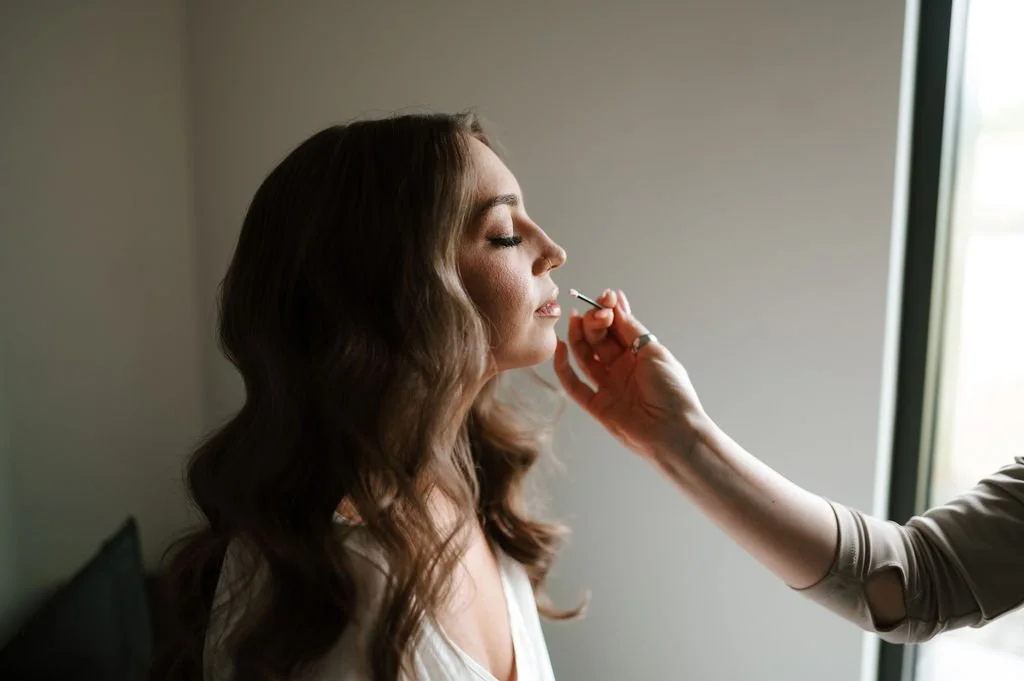 applying lip color for the final makeup touches on a bride