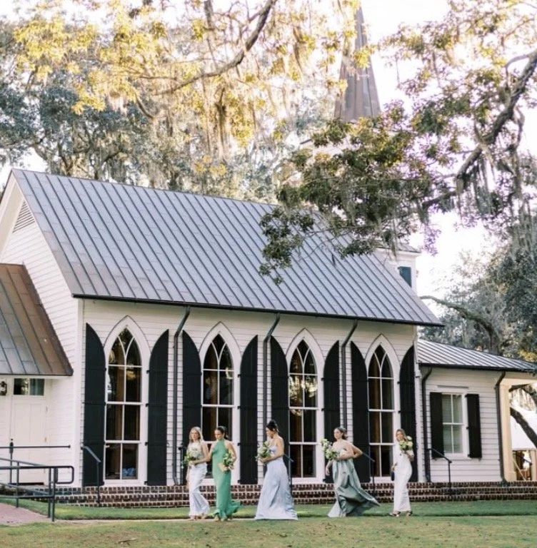 bridesmaids are walking into the somerset chapel wearing soft blue and emerald green dresses