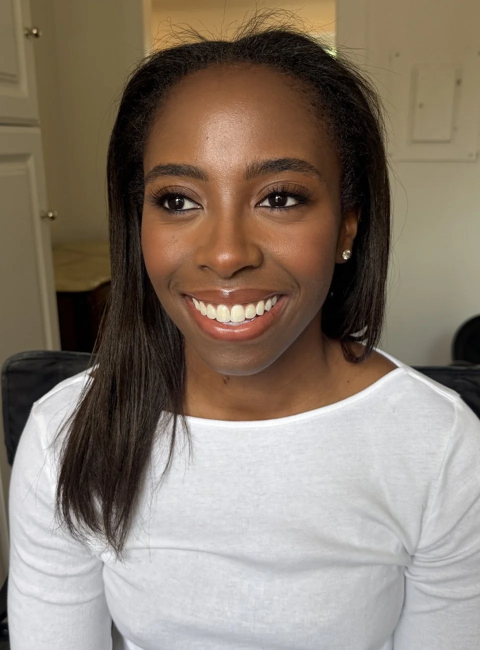 A smiling woman with dark hair and brown skin wearing natural makeup