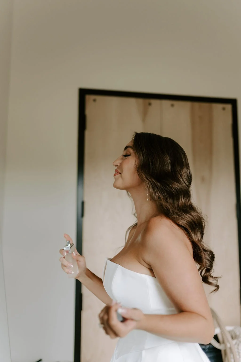 finished bridal hair and bride spraying perfume