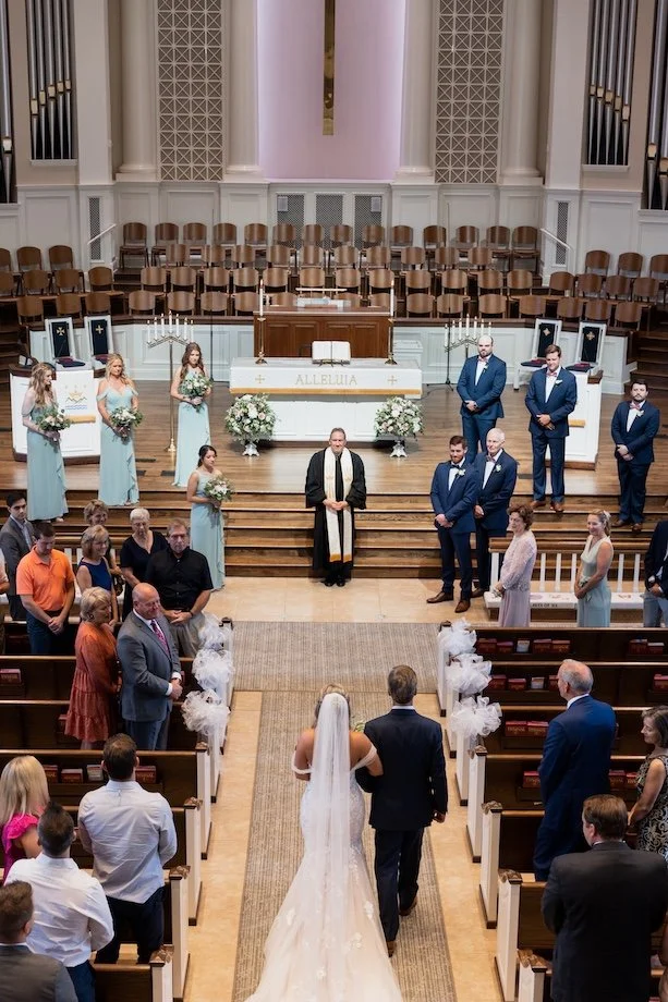 father of the bride and the bride walk down the isle in a traditional church ceremony in atlanta ga