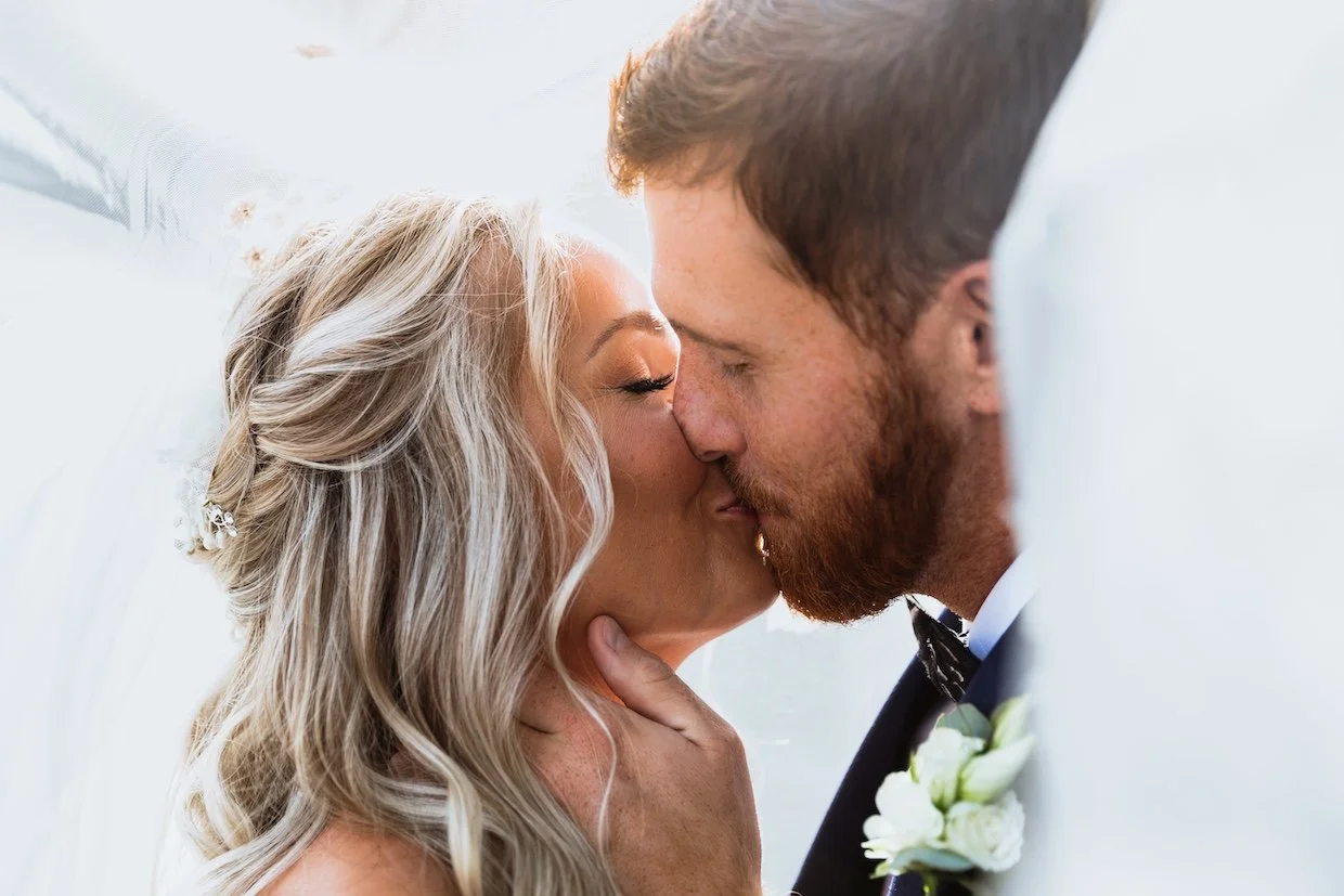 bride and groom close up shot kissing under the veil