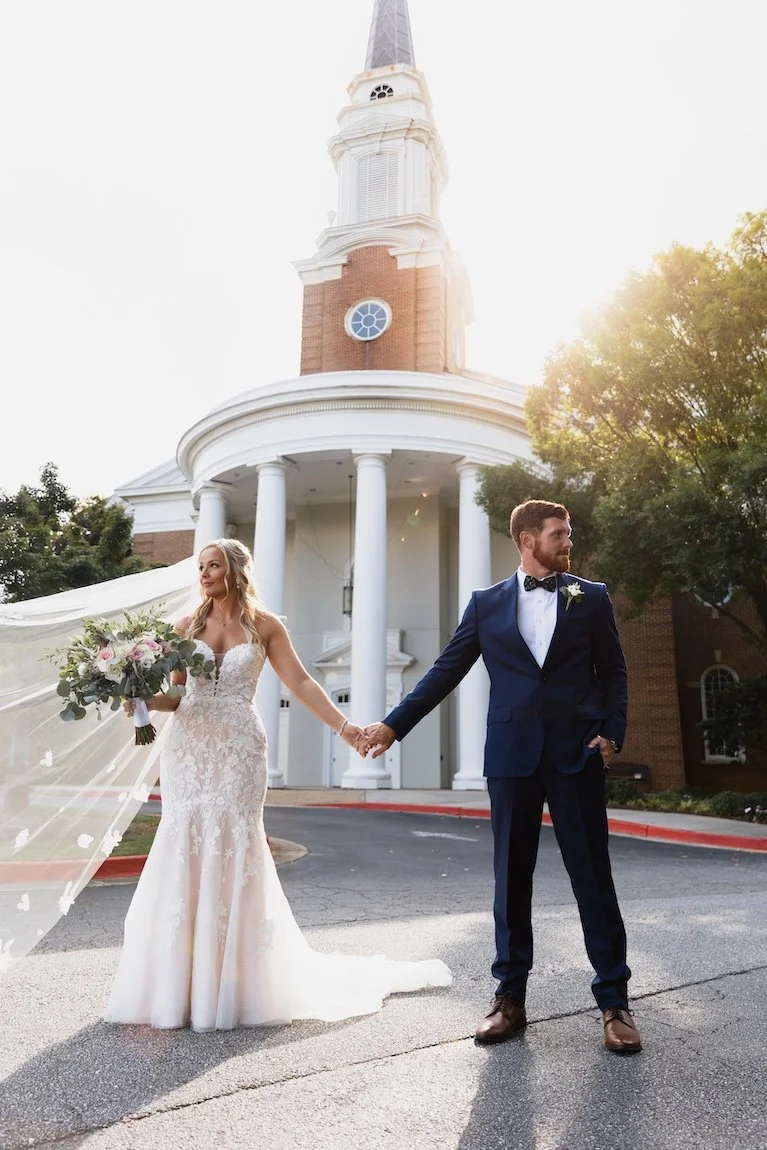 bride and groom standing outside the dunwoody country club holding hands
