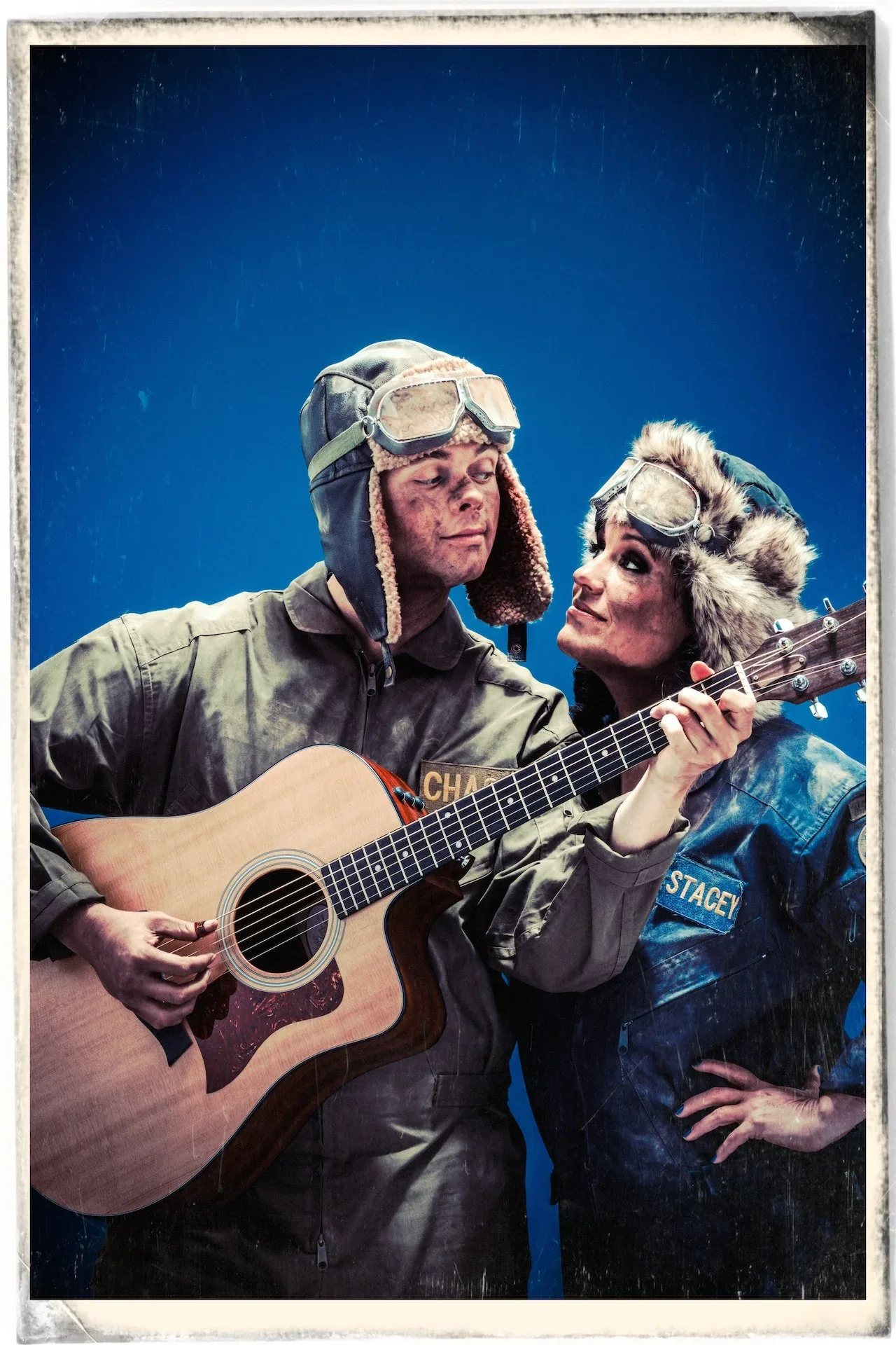 Two characters dressed as soldiers with winter gear, one playing an acoustic guitar and the other looking at him, in a close-up shot against a blue background.
