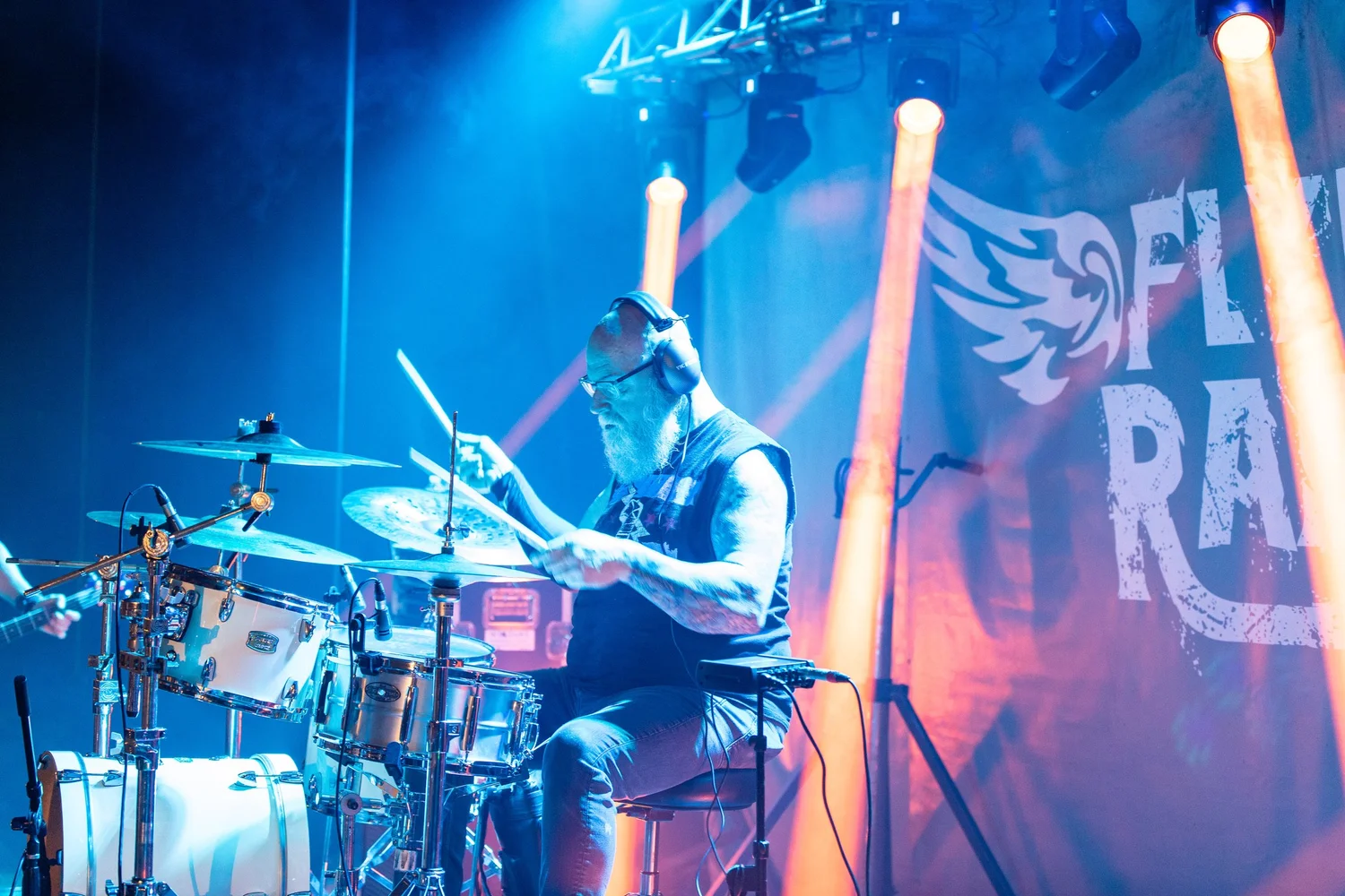 Fly By Radio drummer performing under teal stage lights