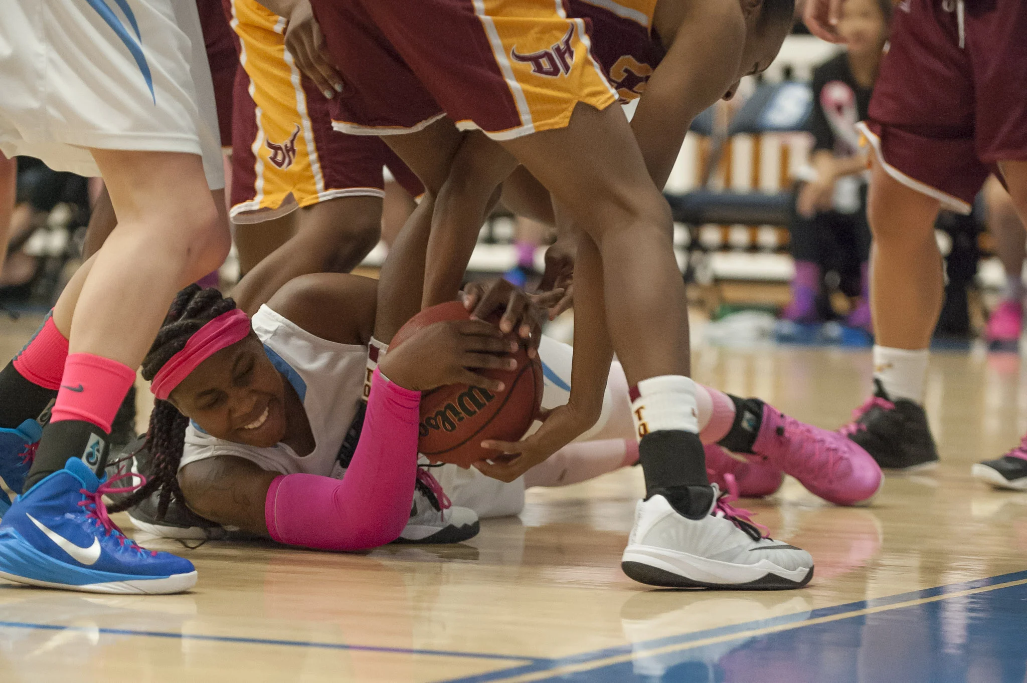 STAR // Connor Gibson Left: Junior Emilee Osagiede wrestles for possession of the ball. Right: Cheerleaders were court side wearing their “Pink the Den” shirts.