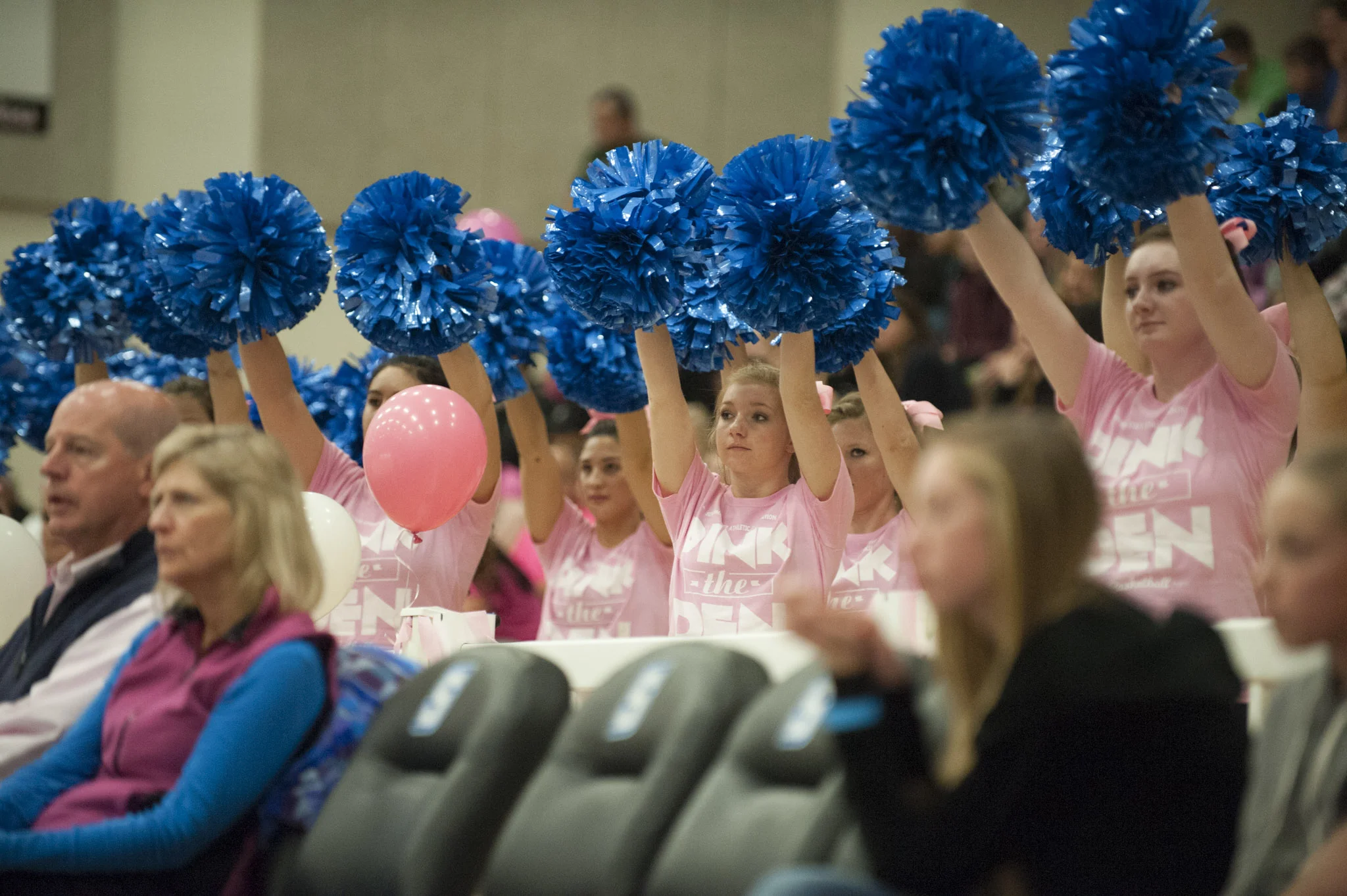 STAR // Connor Gibson Left: Junior Emilee Osagiede wrestles for possession of the ball. Right: Cheerleaders were court side wearing their “Pink the Den” shirts.