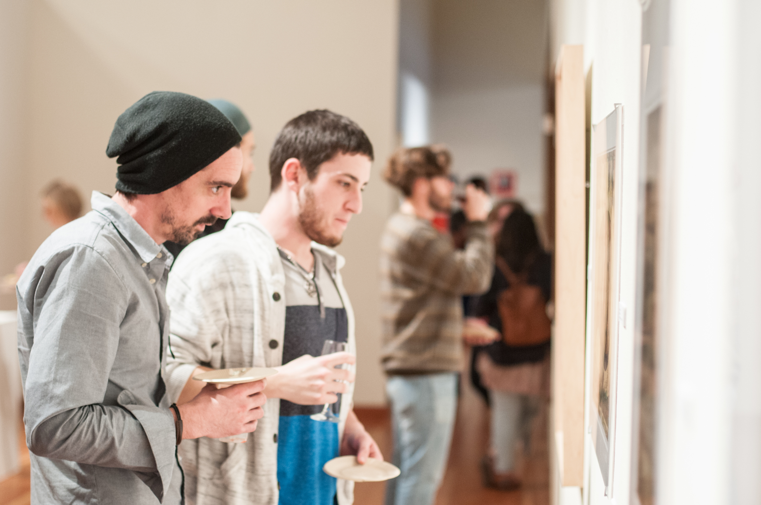 STAR // Gustavo Vasquez Andrew Scanlon, art studio sculpture major and Vinnie Schraner, art studio painting major, examining artwork showcased at the Faculty Art Show on Thursday during the University Art Gallery reception.