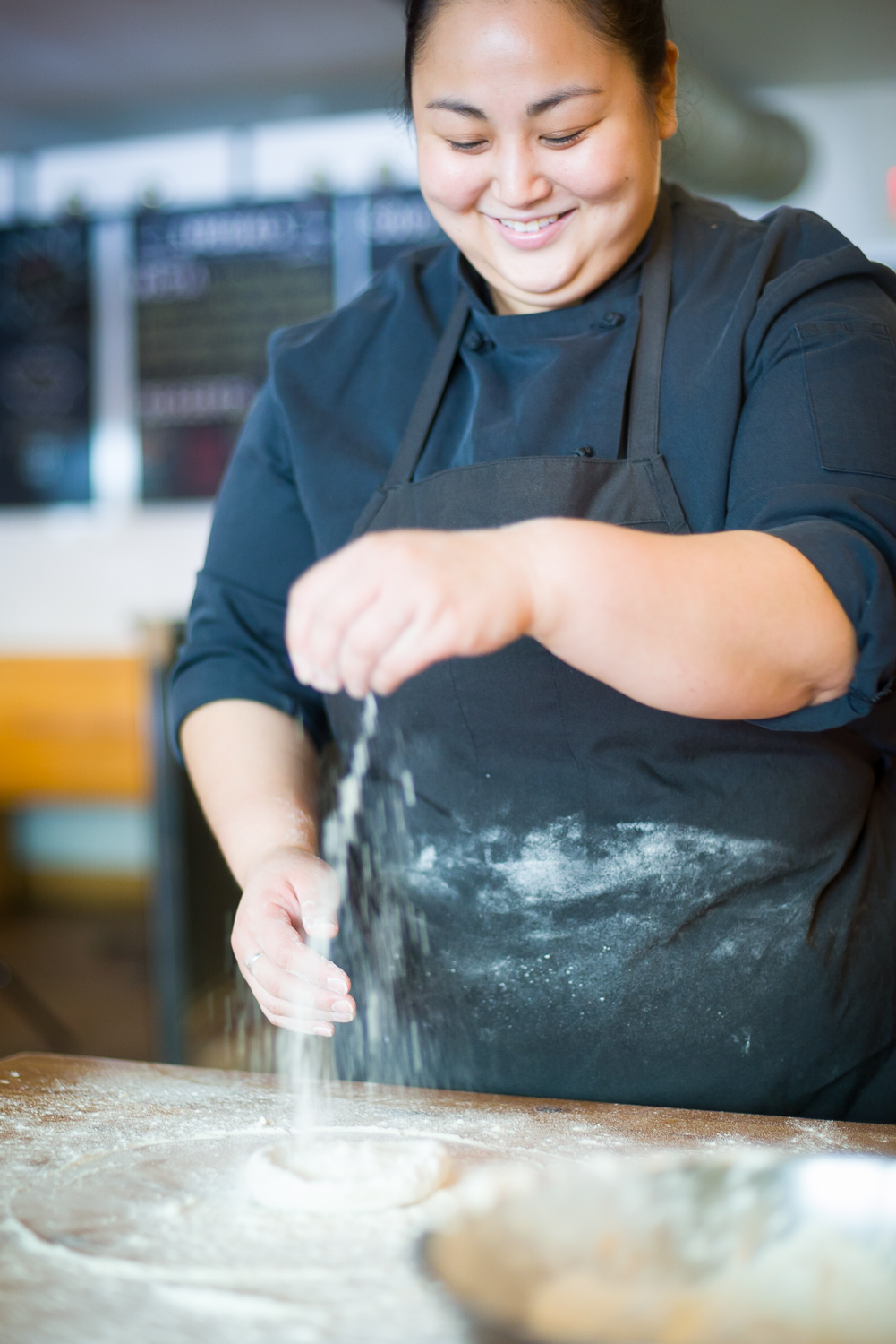 Smiling young woman chef with dough