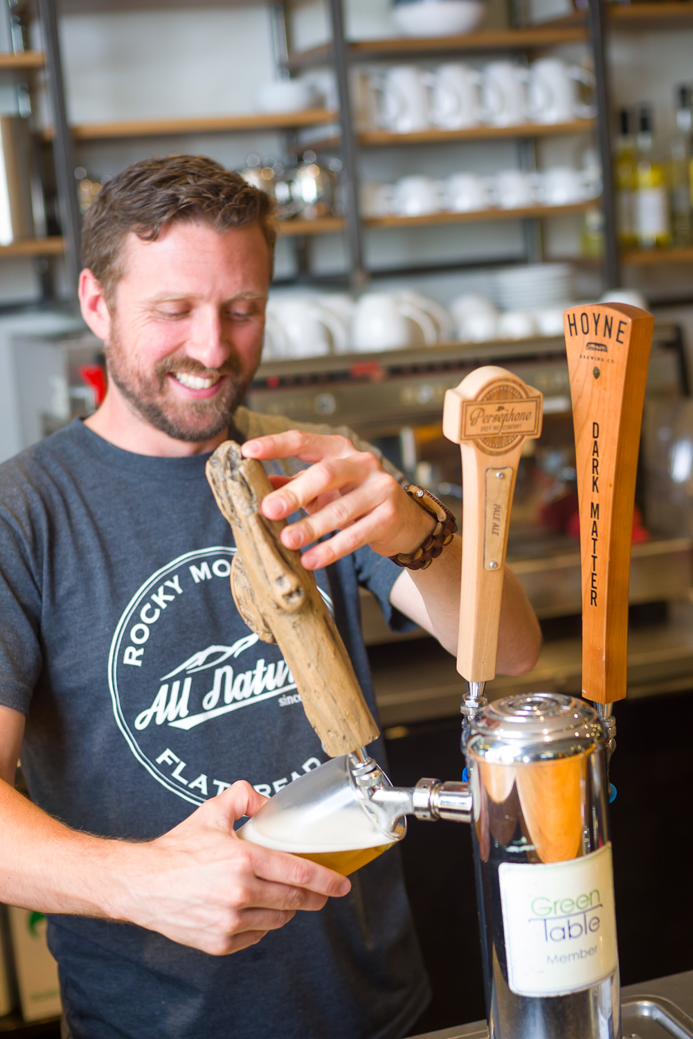 Smiling middle aged male bartender with beard pouring a beer from a tap lifestyle